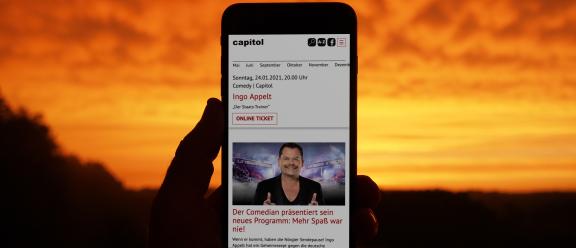 Website des Capitol auf einem Smartphone vor einem Sonnenuntergang im Freien.