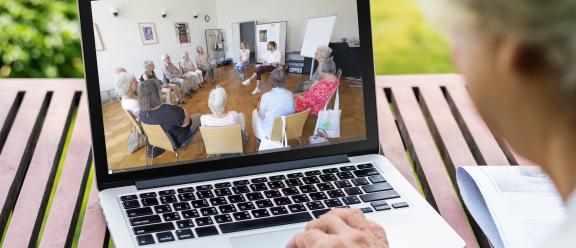 Eine ältere Dame sieht sich im Freien auf einem Laptop ein Video auf der Website von LiFE-Alltagsübungen an